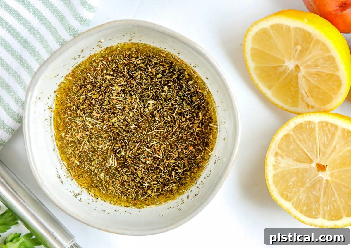 Greek chicken marinade prepared in a small bowl with fresh lemon halves to the side, showcasing the vibrant ingredients.