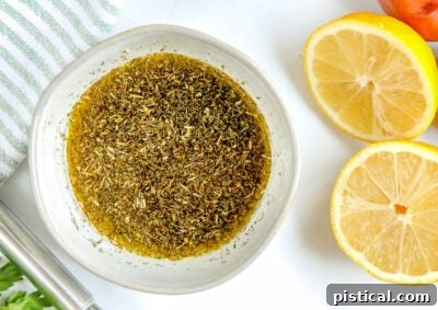 Greek chicken marinade prepared in a small bowl with lemon halves to the side, highlighting the key ingredients for flavor.