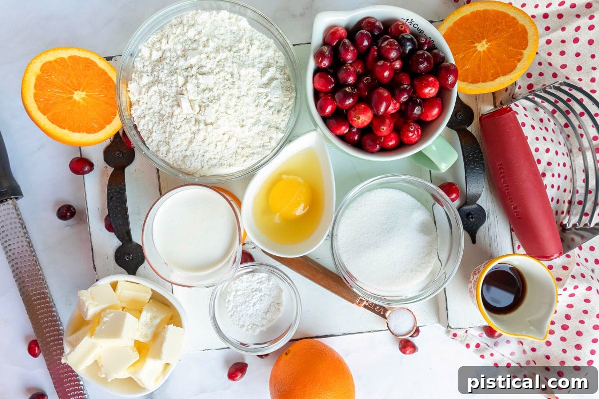 Individual ingredients for cranberry orange scones, measured out in small bowls, including flour, sugar, butter, cranberries, and orange zest