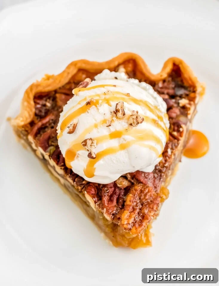 A tempting slice of maple pecan pie, drizzled with caramel and topped with a scoop of creamy vanilla ice cream, on a white plate.