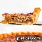 slice of pecan pie on pie server with pie beneath