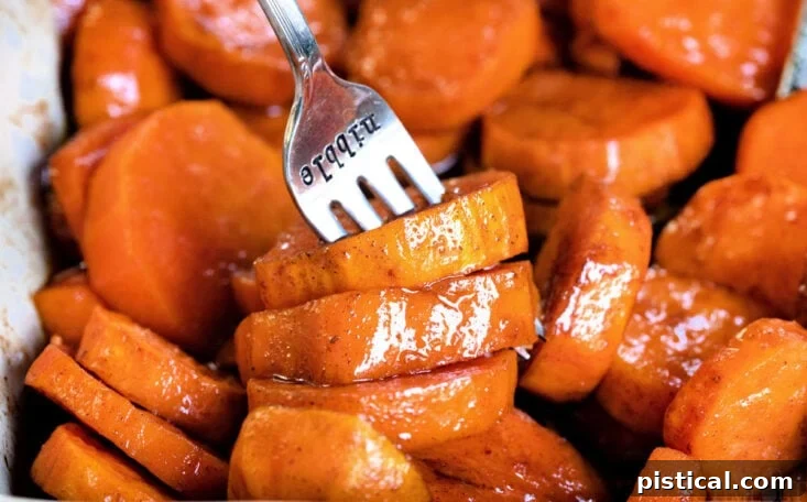 Candied yams in a baking dish with a fork resting in it, ready to be eaten
