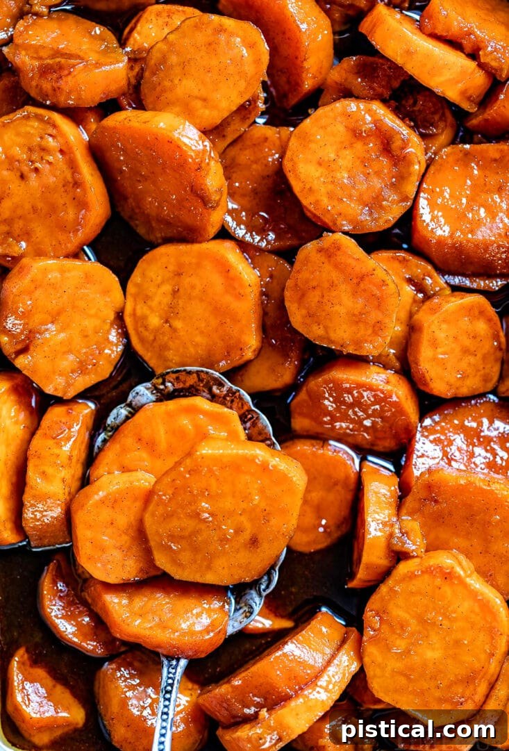 Close-up of candied yams in a baking dish, top-down view, with a spoon of yams at the bottom