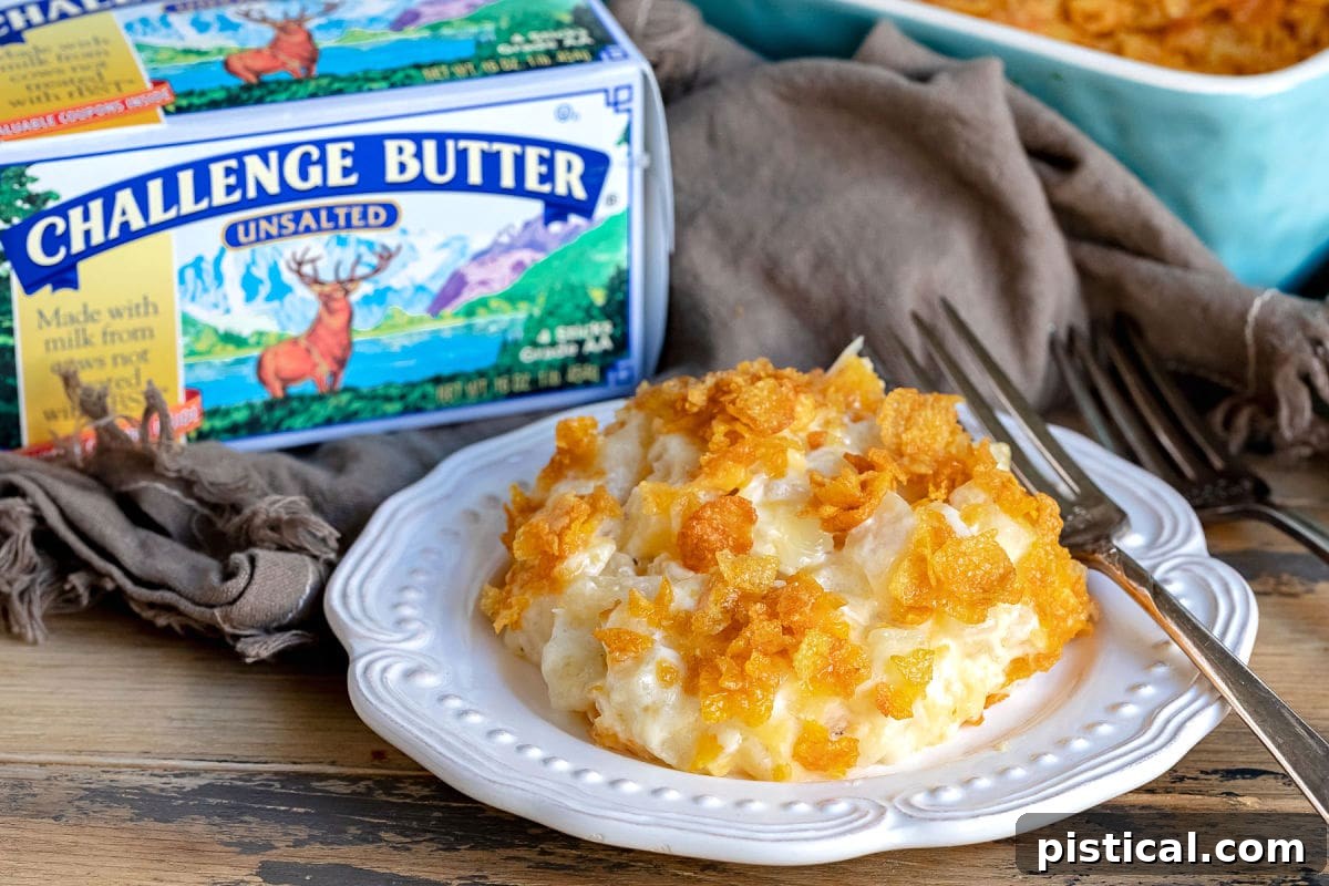 Homestyle Cheesy Potato Casserole 4 A close-up of a portion of cheesy potatoes on a white plate, with a Challenge Dairy butter box visible in the background, highlighting ingredient quality.