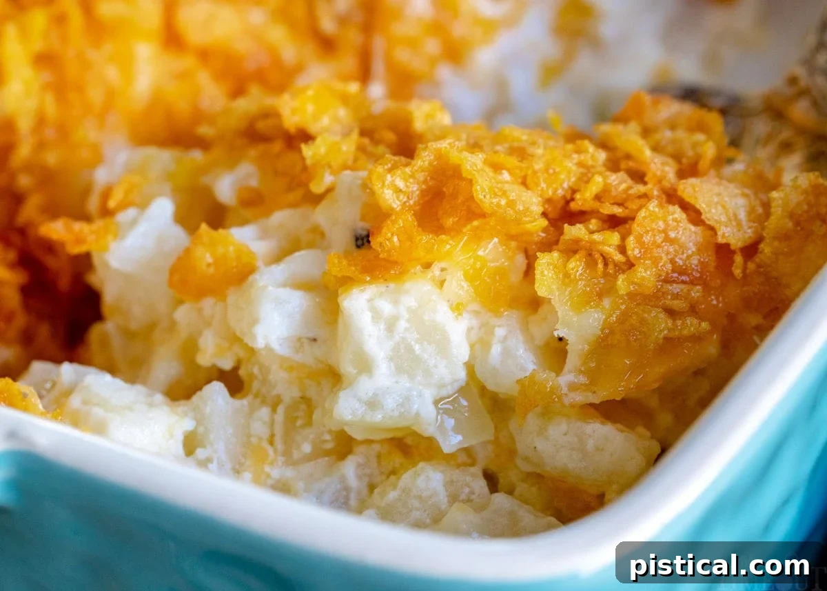 Homestyle Cheesy Potato Casserole 8 A casserole dish filled with golden-brown funeral potatoes and a serving on a white plate, with a Challenge Dairy butter box in the background.