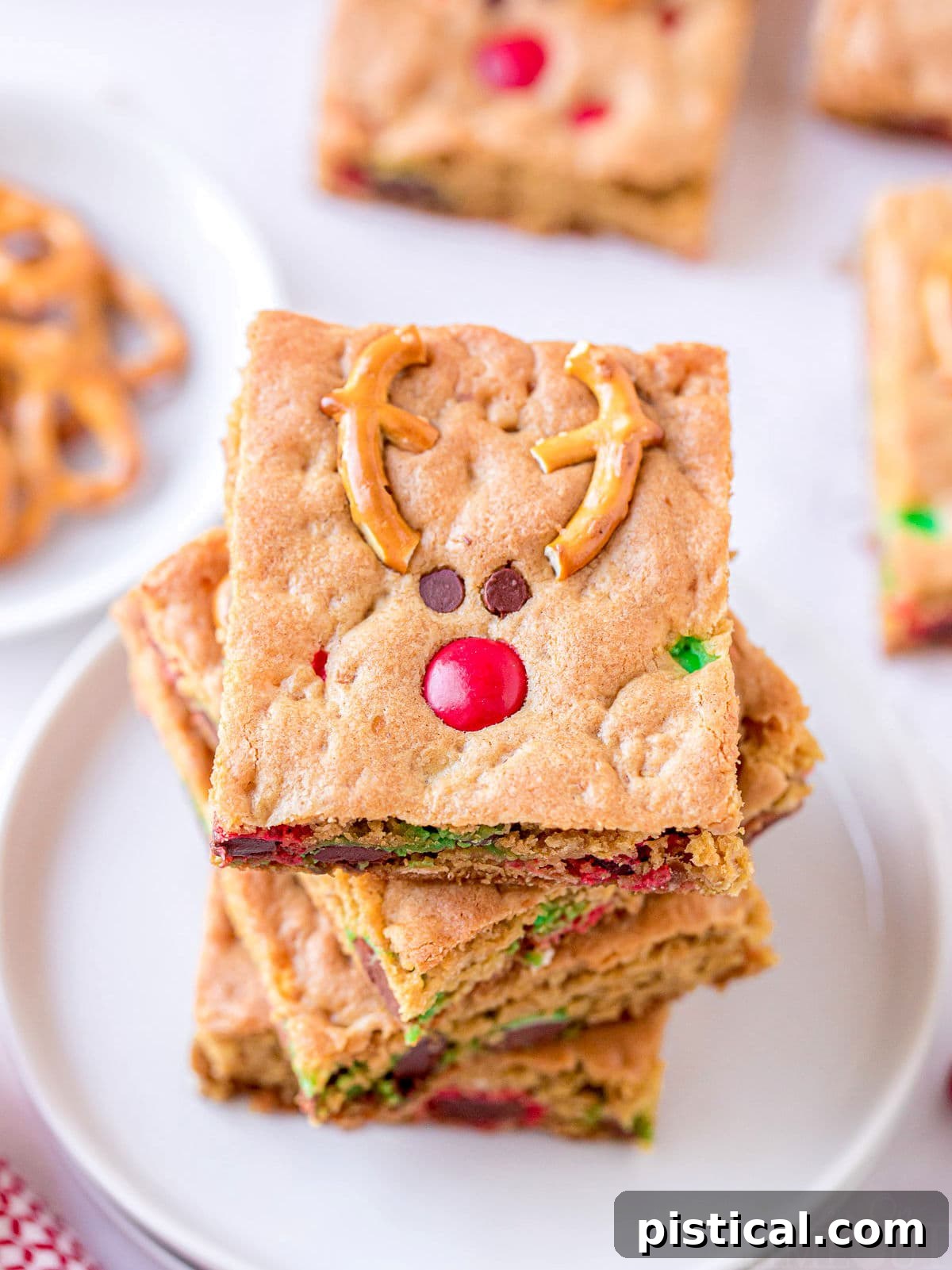 Top-down view of four Reindeer Cookie Bars neatly stacked on a white plate, ready to be enjoyed.
