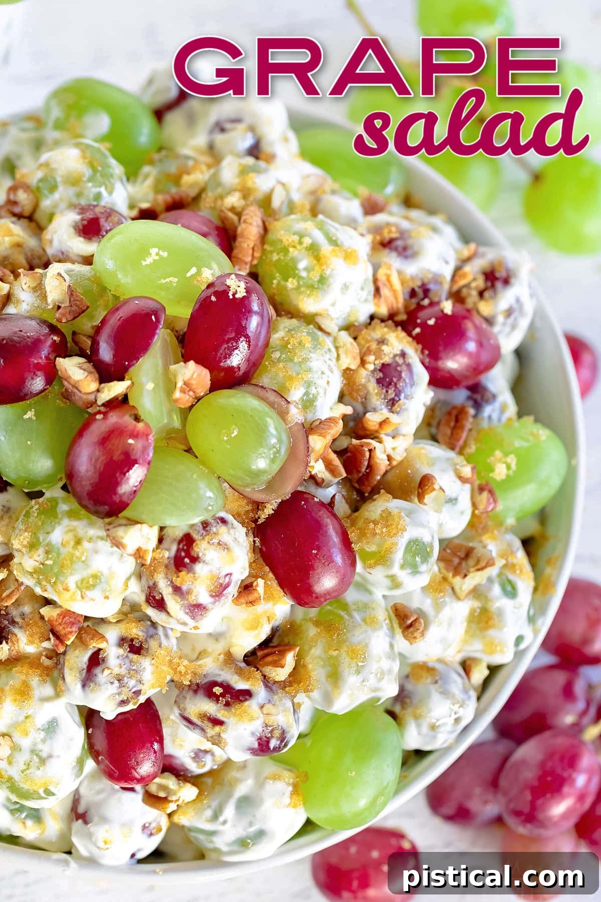 top down view of grape salad in clear bowl topped with cut grapes and pecans and brown sugar with a title overlay at top of image