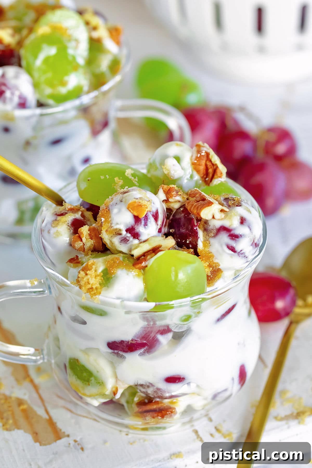 grape salad with cream cheese dressing in small cup with gold spoon