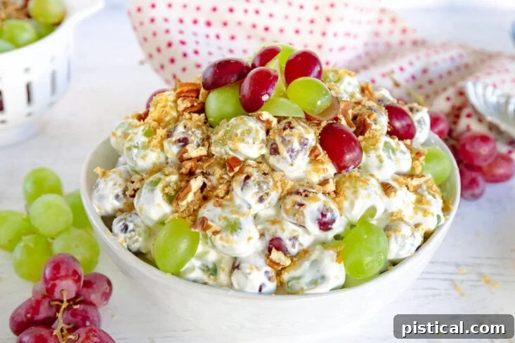 grape salad with creamy cream cheese dressing topping with brown sugar and pecans in white bowl with grapes around it