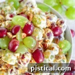top down view of grape salad in clear bowl topped with cut grapes and pecans and brown sugar