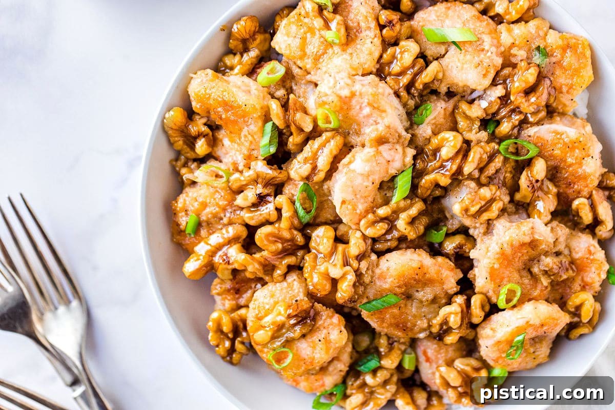 Sweet & Savory Walnut Shrimp Delight 3 An overhead shot of Honey Walnut Shrimp in a white bowl, generously garnished with chopped green onions, with two forks resting beside the dish, highlighting its inviting presentation.