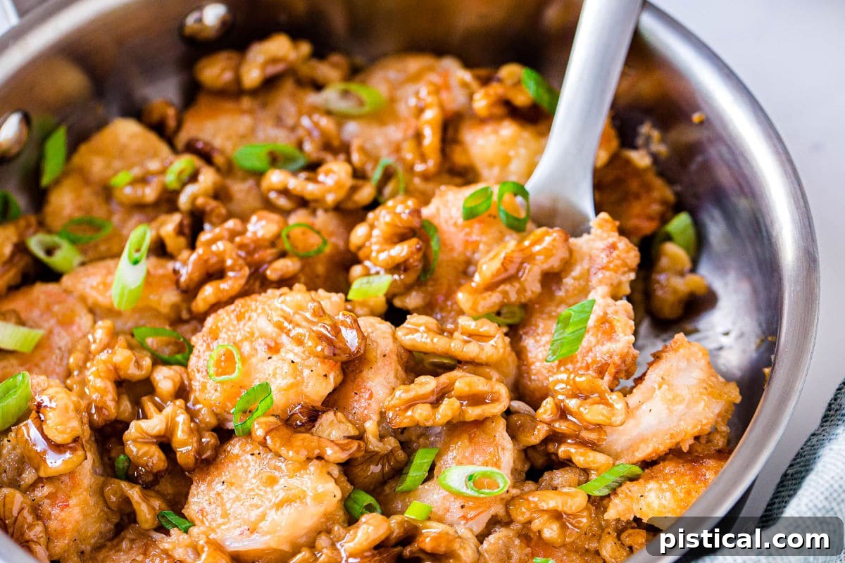 Sweet & Savory Walnut Shrimp Delight 8 A shot of Honey Walnut Shrimp still in the skillet, with a serving spoon scooping out a portion, emphasizing the rich coating and textures.