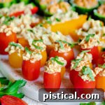 close up of stuffed hummus veggies topped with fresh herbs