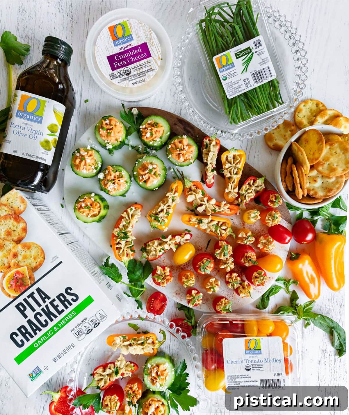 A flat lay photograph showcasing the completed hummus stuffed veggie tray surrounded by all the fresh ingredients and hummus containers used to create it.
