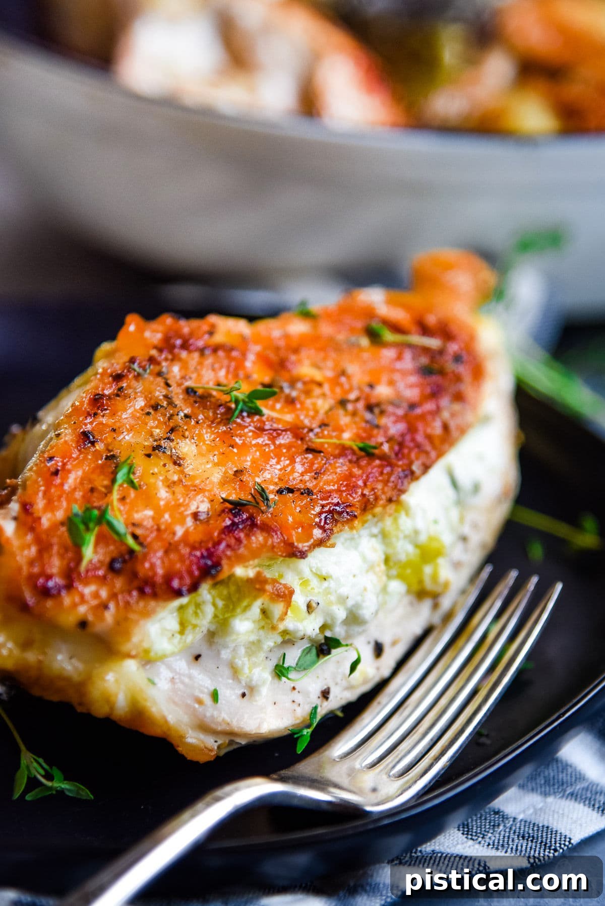 Stuffed chicken breast with crispy skin served on a black plate with a fork