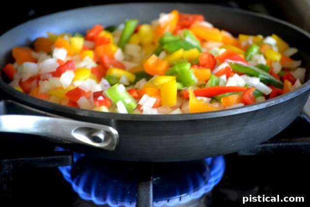 Fresh vegetables being sautéed in a skillet for spaghetti sauce