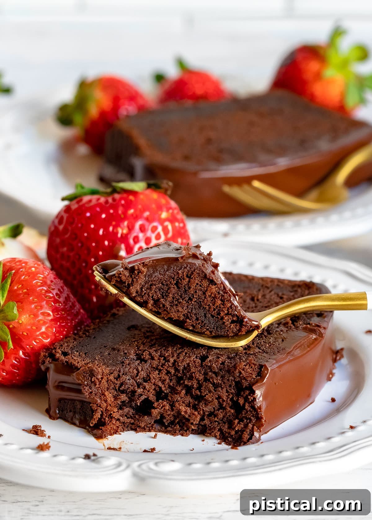 Decadent Chocolate Loaf 2 A perfectly portioned slice of moist chocolate pound cake, with a fork gently taking a bite, served on a pristine white plate alongside fresh, vibrant strawberries, and another cake slice blurred in the background.