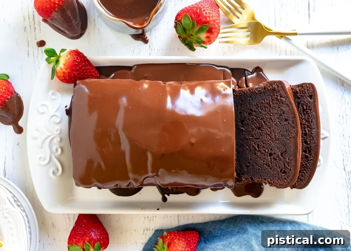 Decadent Chocolate Loaf 11 A beautifully baked chocolate pound cake, generously coated with a glistening chocolate ganache glaze, presented on a pristine white tray with two perfect slices already cut and ready to be enjoyed.