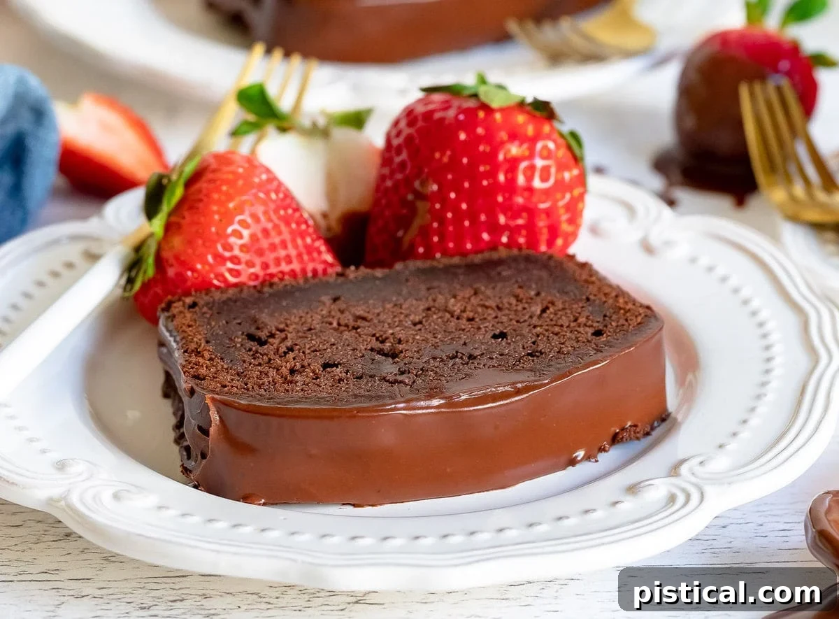 Decadent Chocolate Loaf 12 A pristine slice of moist chocolate pound cake, elegantly presented on a white plate, garnished with vibrant fresh strawberries, highlighting its rich texture and inviting appearance.