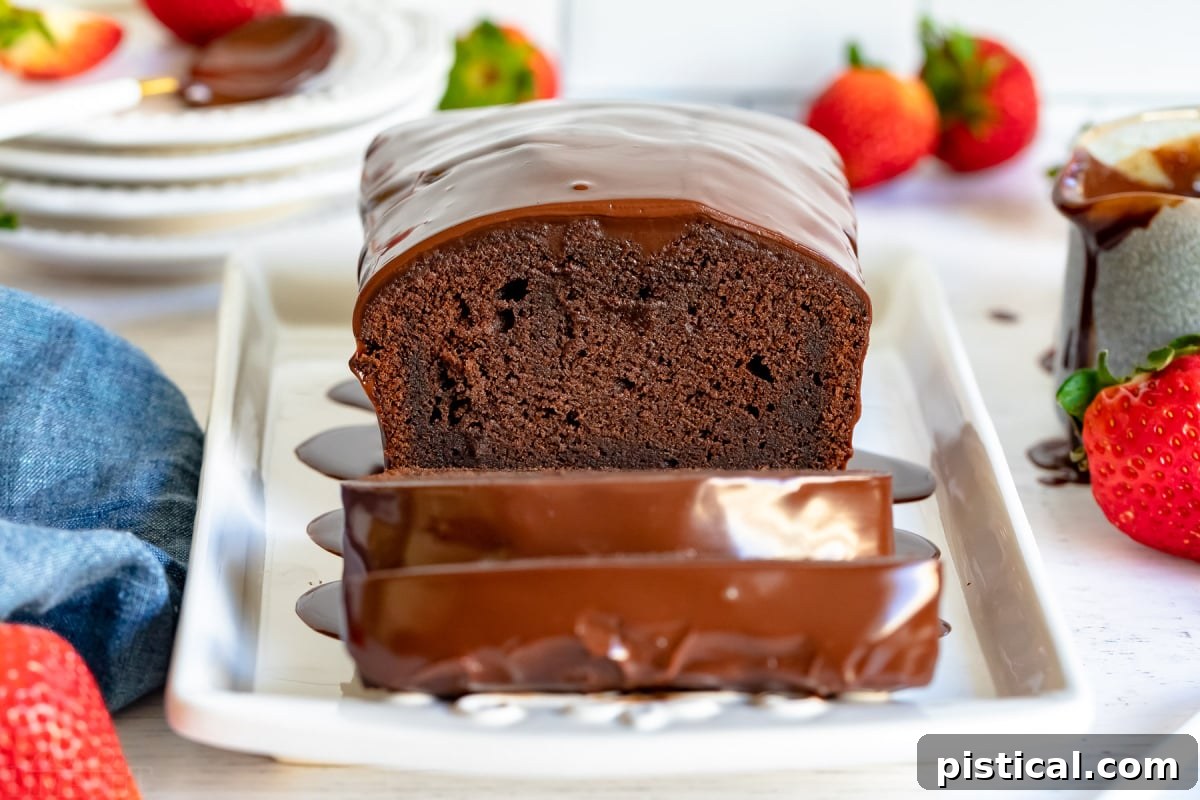 Decadent Chocolate Loaf 5 A whole chocolate pound cake loaf, with several neat slices taken, presented on an elegant white platter. Accompanying it are two golden forks and a playful scattering of fresh strawberries, all resting on a blue napkin to the left.