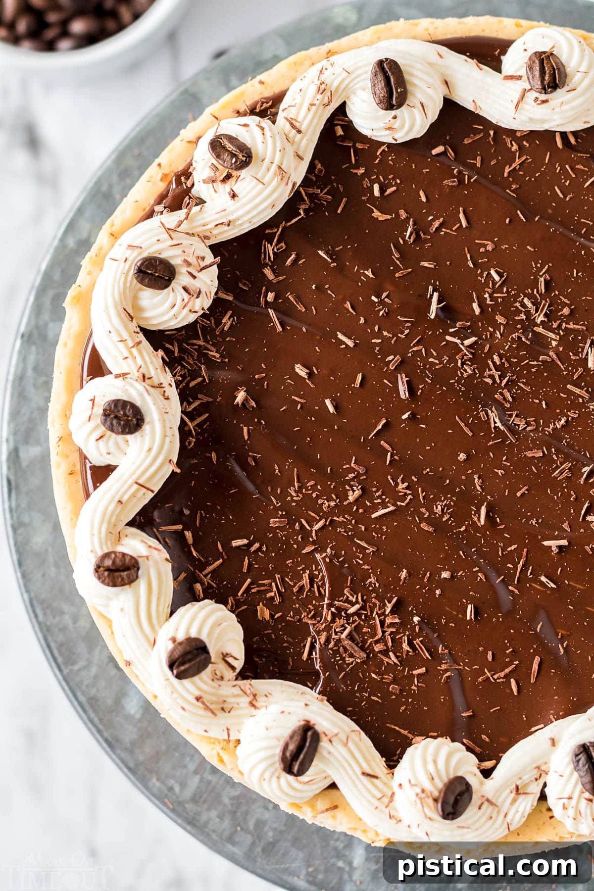 An overhead shot showcasing a whole espresso cheesecake, glistening with ganache and artfully decorated, presented on a elegant metal cake stand.