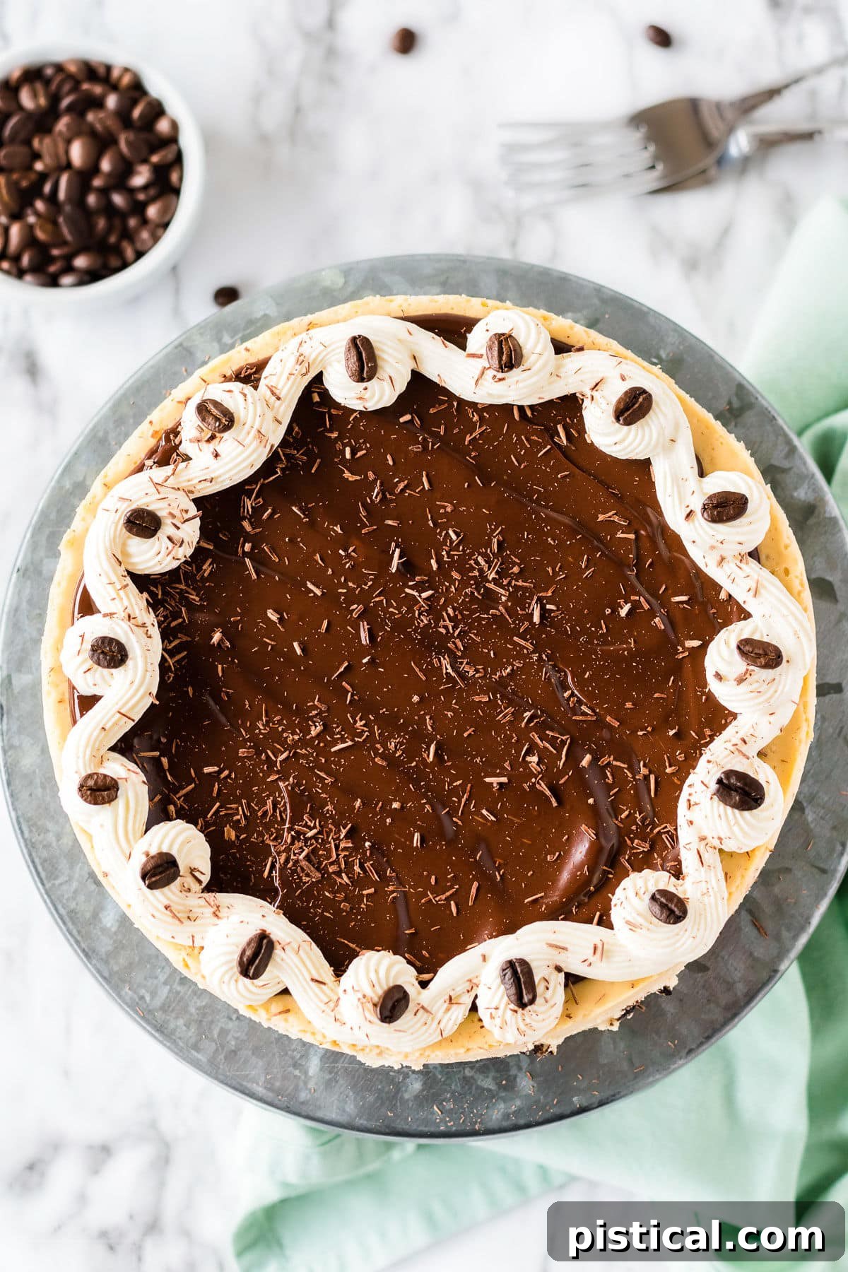 A rich espresso cheesecake, beautifully coated in a smooth chocolate ganache and adorned with fine chocolate shavings, ready to be served.