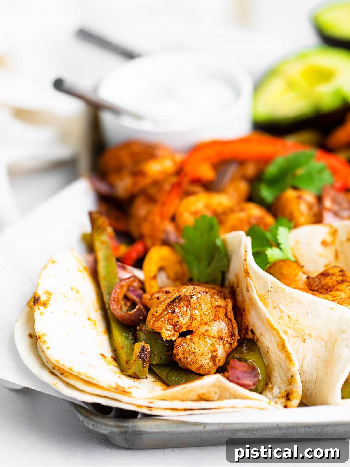 Sizzling Sheet Pan Shrimp Fajitas 3 a couple of fajitas on a sheet pan topped with fresh cilantro.
