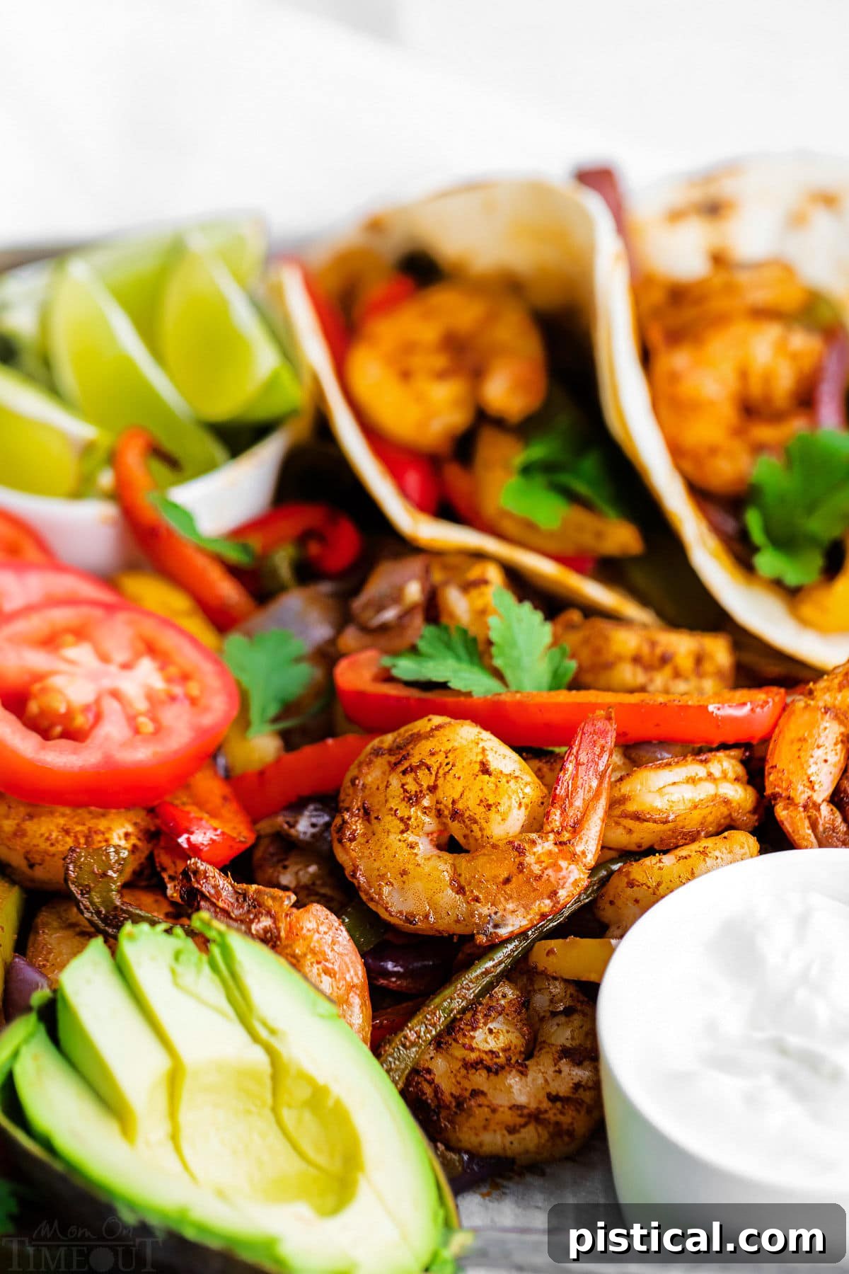 Sizzling Sheet Pan Shrimp Fajitas 4 close up look at the shrimp fajitas on sheet pan with sliced avocado and sour cream.
