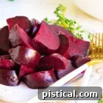 How to Make Perfect Roasted Beets 9 Roasted beets, cut up and arranged on a white plate with white and gold forks and thyme in the background.