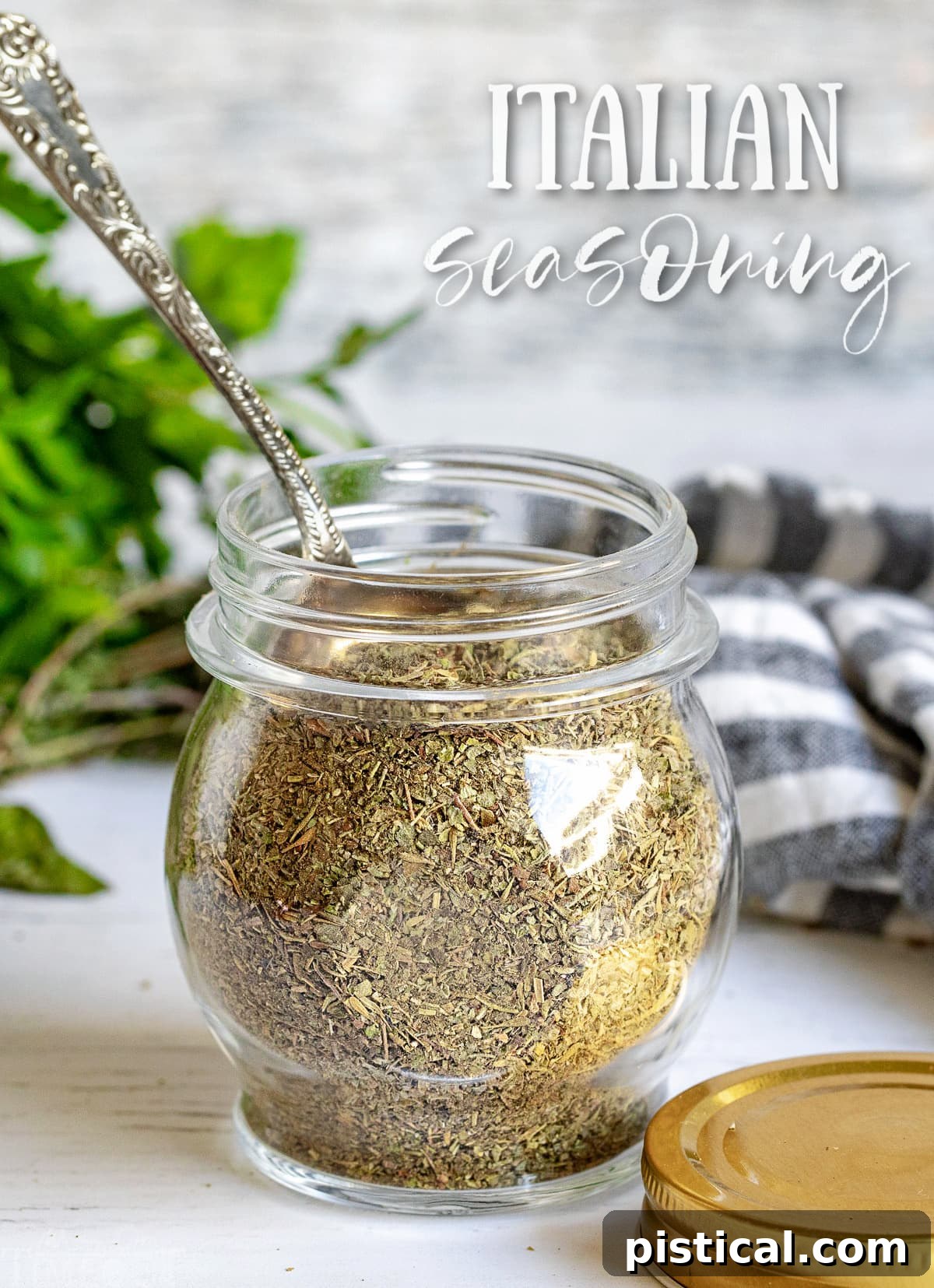 Homemade Italian seasoning in a small glass jar with a spoon, ready to be used in various dishes.