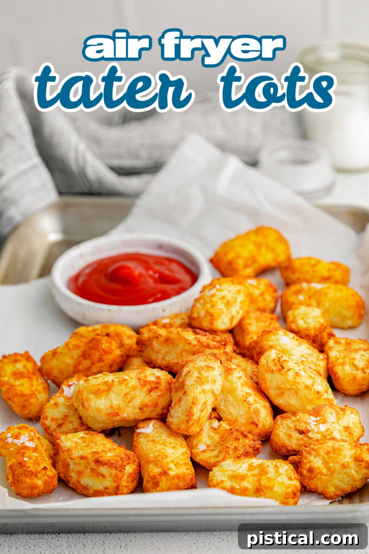 Crispy golden tater tots served on a sheet pan with a small bowl of ketchup, ready to be enjoyed.