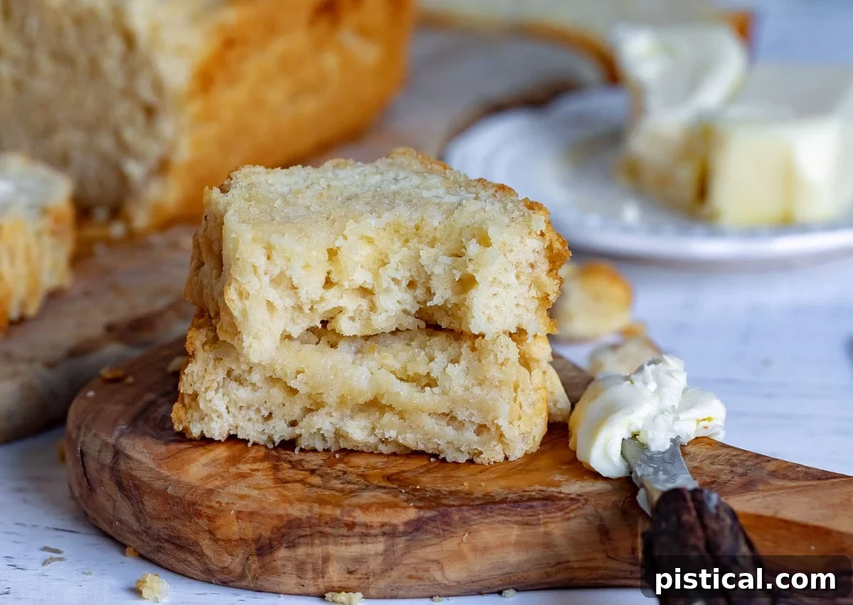 A thick slice of beer bread, cut in half, with melted butter seeping into its soft texture.