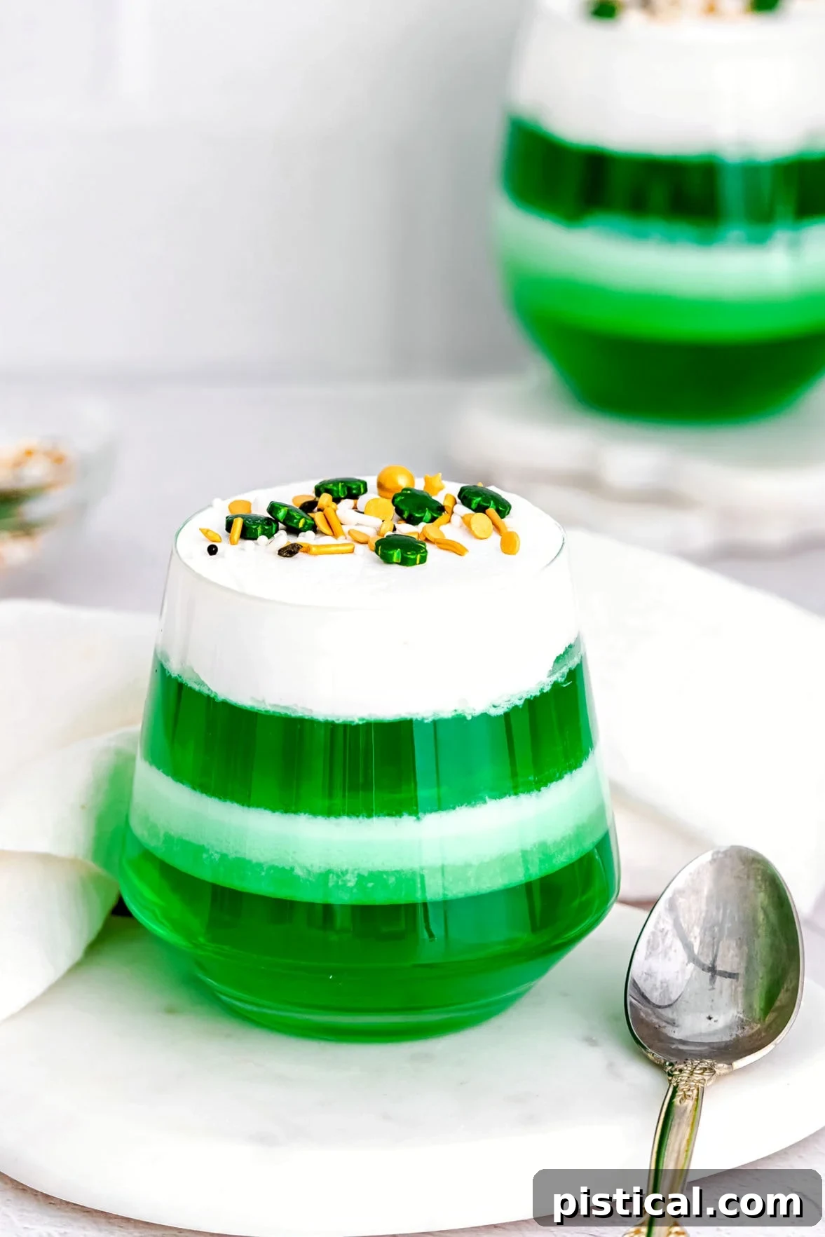 layered green and white jello cups on marble surface.