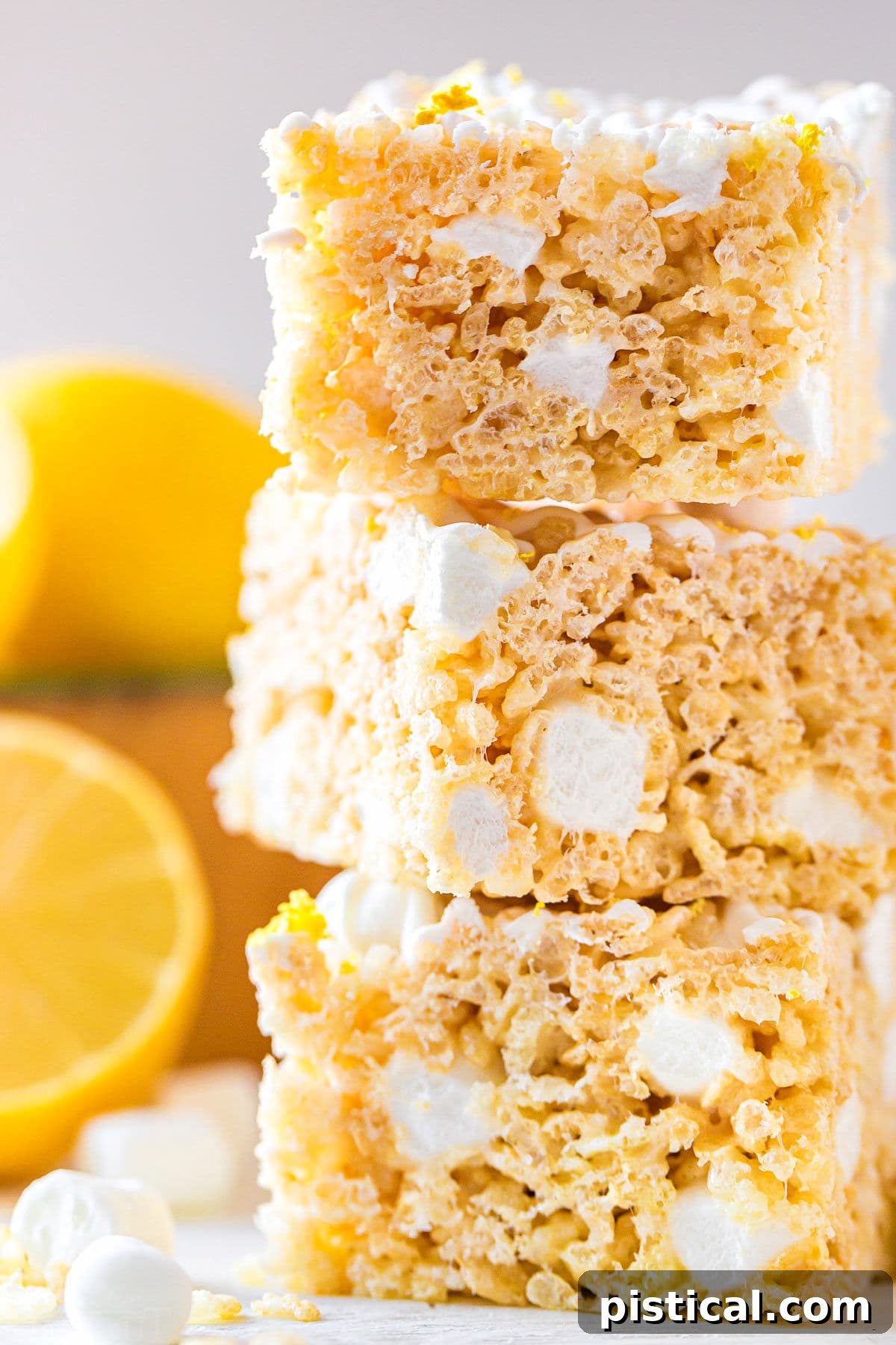 Zesty Lemon Krispie Squares 3 A close-up view of three perfectly stacked lemon rice krispie treats, showcasing their gooey texture and inviting appearance.