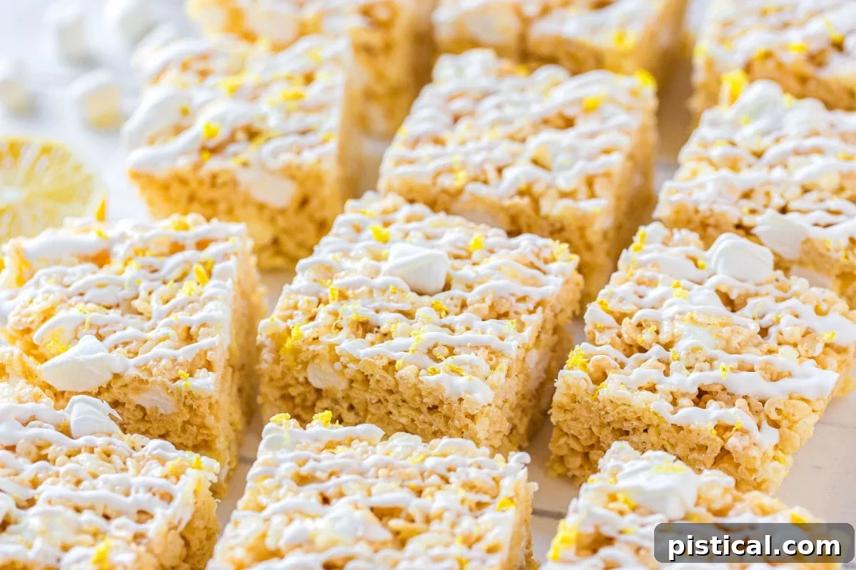 Zesty Lemon Krispie Squares 7 Perfectly portioned lemon rice krispie treats arranged on a pristine white surface, each topped with a delicate white drizzle.