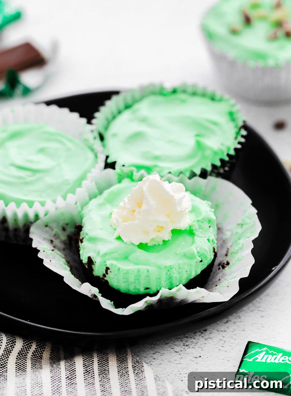 Three perfectly formed Grasshopper Mini Cheesecakes arranged on a sleek black plate, showcasing their inviting green color and smooth texture.
