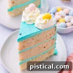 a slice of easter cake with bright blue frosting decorated with cadbury eggs.