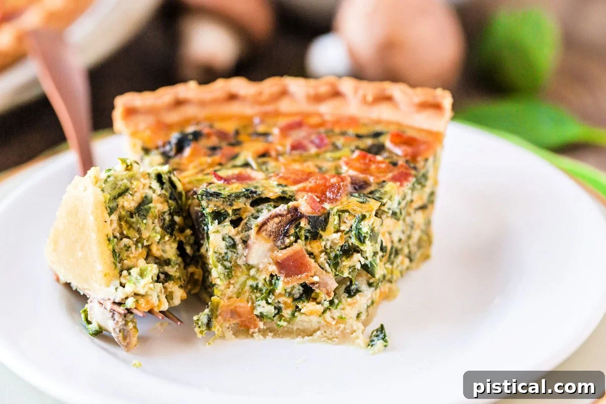 A delicious slice of spinach quiche with a bite taken out, resting on a white plate, revealing its rich filling.