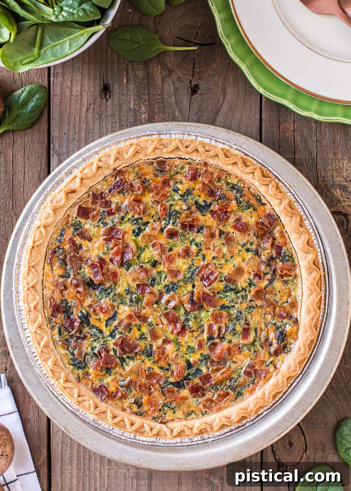 A beautiful, whole Spinach Quiche sitting on a rustic wooden surface, ready to be sliced and served.