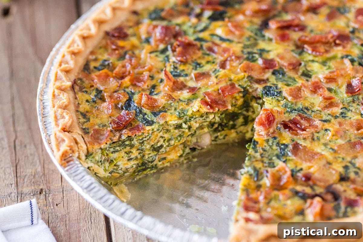 A perfectly baked Spinach Quiche with a slice removed, showcasing its delicious, golden-brown crust and vibrant filling.