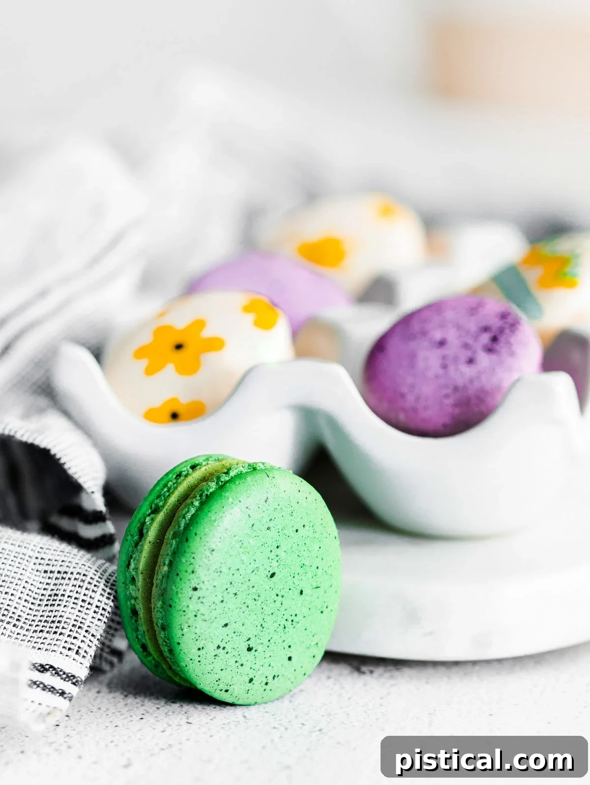 Pastel Easter Macarons 3 green speckled macaron sitting in front of egg tray.