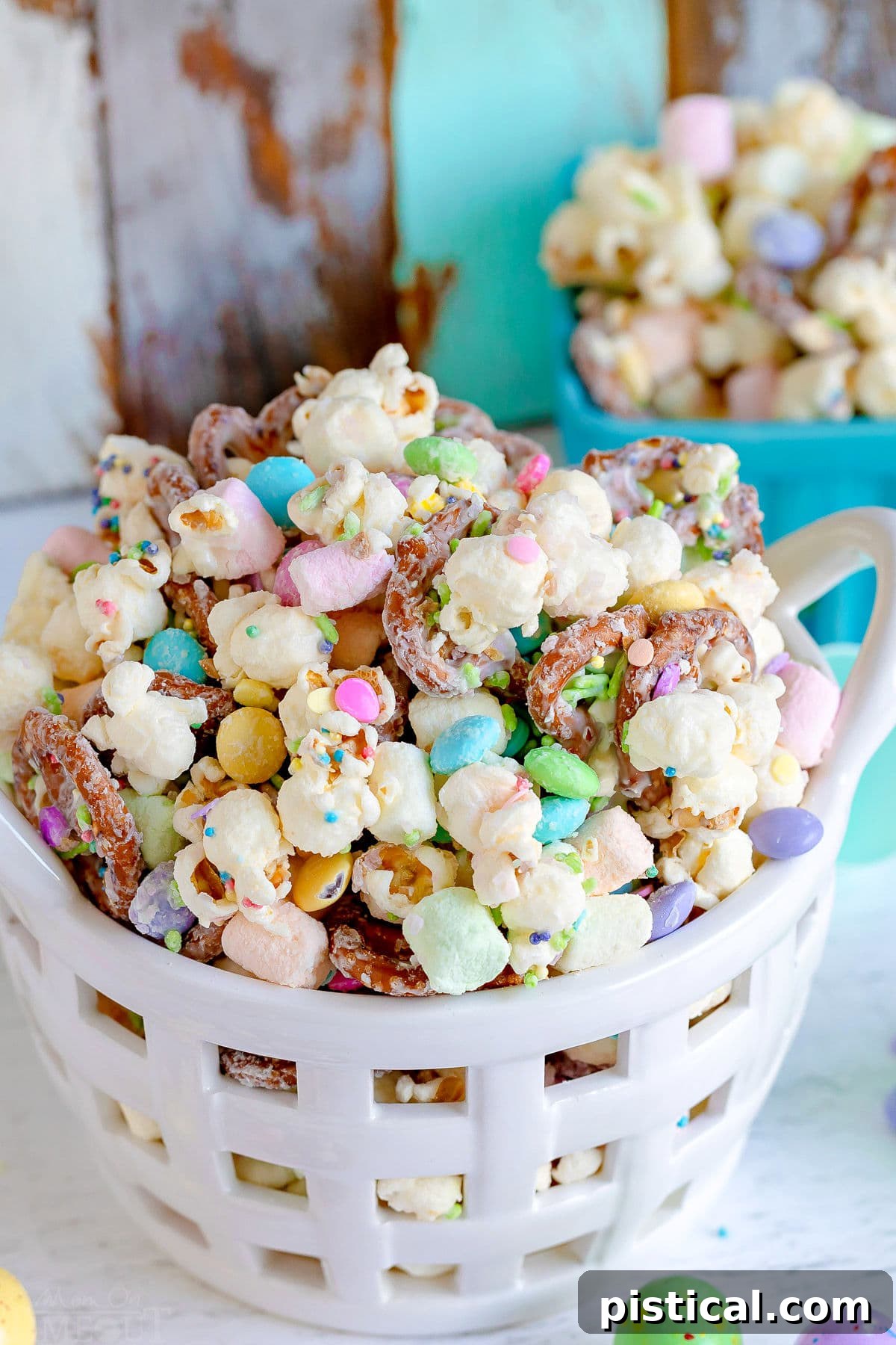 Spring Bunny Trail Mix 7 A charming white ceramic basket filled to the brim with Bunny Bait snack mix, showcasing the delightful combination of popcorn, pretzels, and colorful Easter candies.