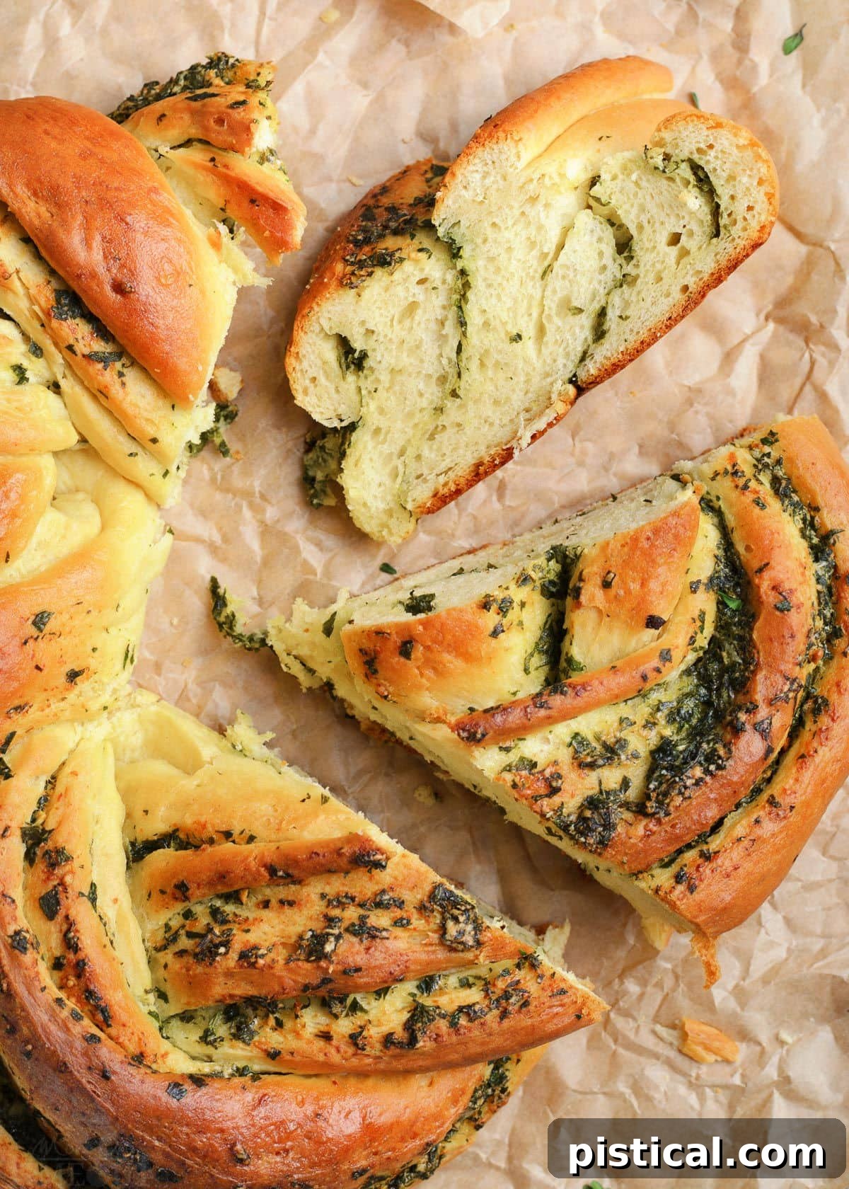 Top-down view of the baked garlic herb bread wreath, with several pieces gently pulled apart, revealing the soft, herby interior.