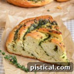 A freshly baked piece of garlic herb bread on brown parchment paper, used as a thumbnail for the recipe.