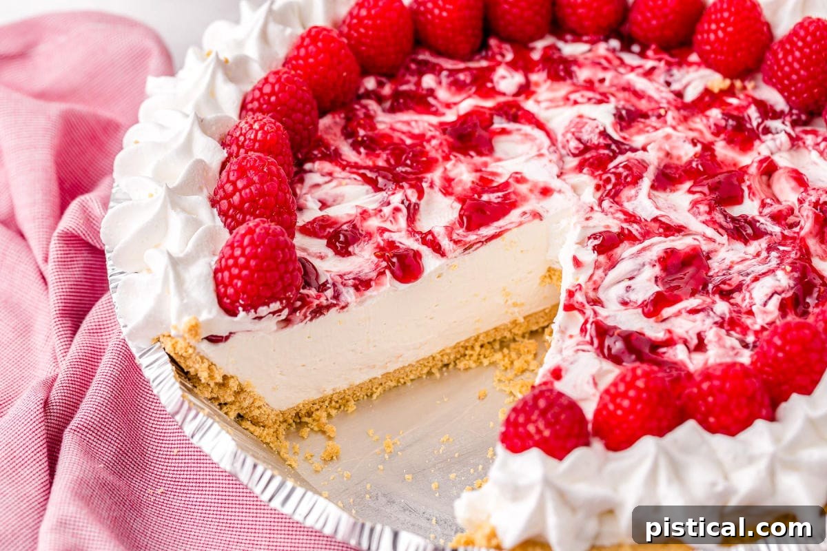 Refreshing Raspberry Cheesecake 5 A whole raspberry cheesecake with one slice perfectly removed, sitting next to a soft pink towel.