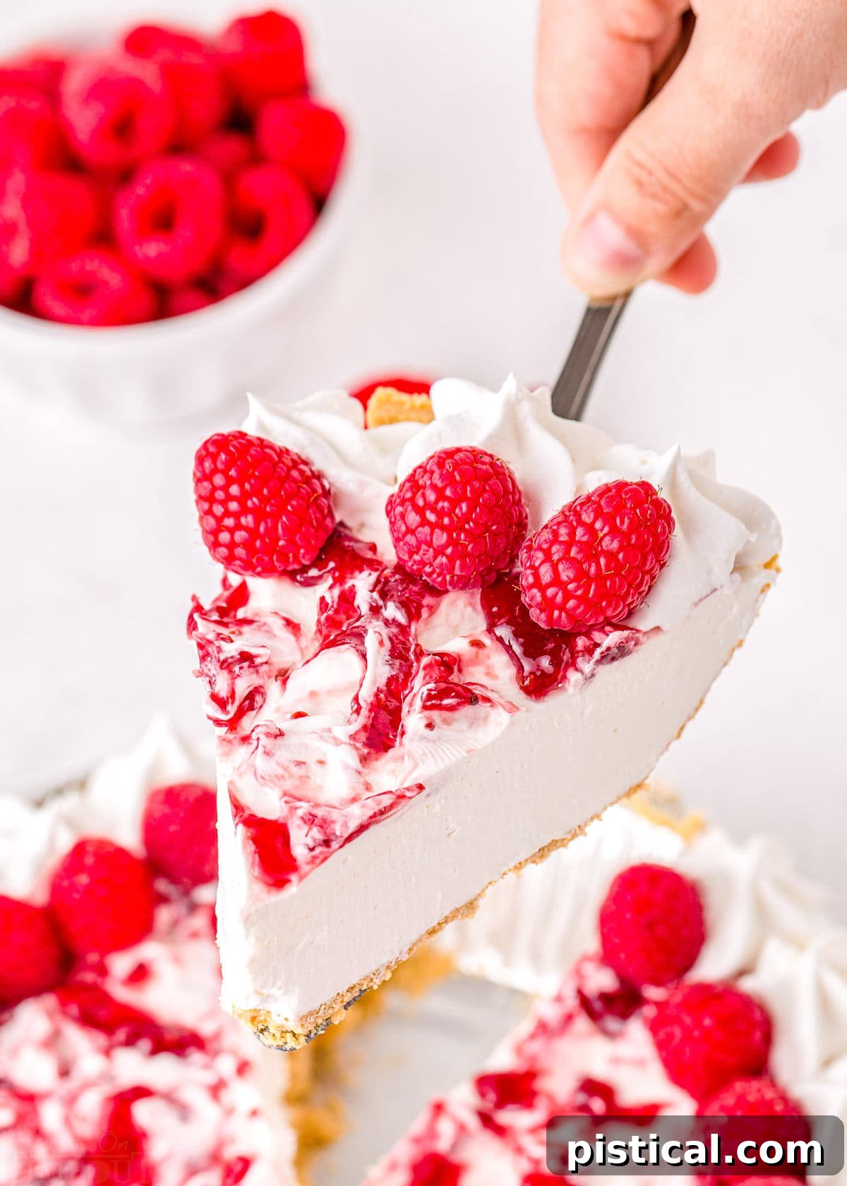 Refreshing Raspberry Cheesecake 8 A slice of no-bake cheesecake with a luscious raspberry topping being served with a pie server from the full cake.
