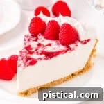 A delectable slice of no-bake raspberry cheesecake on a plate, garnished with fresh raspberries, ready to be enjoyed.