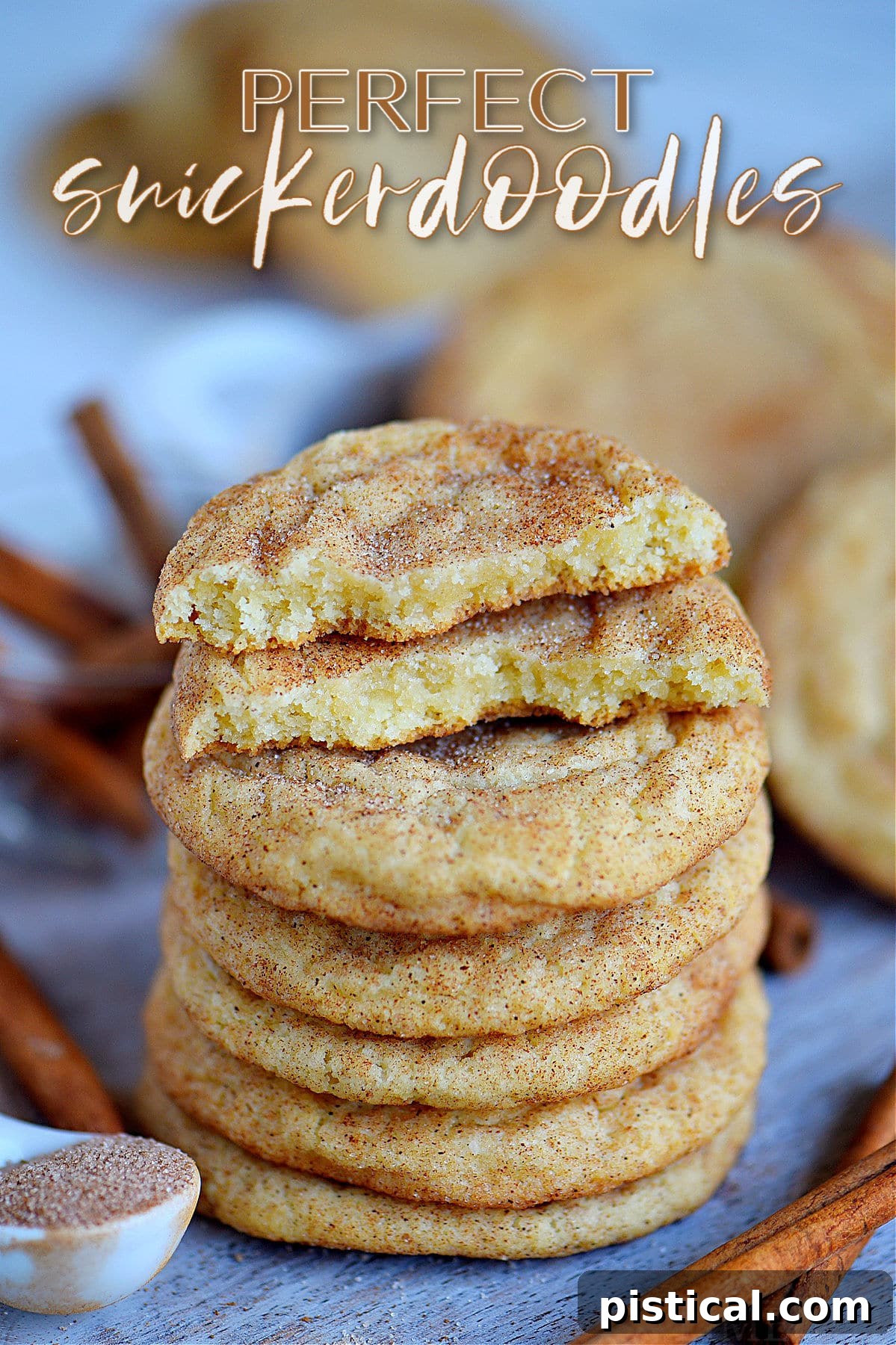 Stacked soft and chewy snickerdoodle cookies on a blue board with one cookie broken in half to show its soft interior.