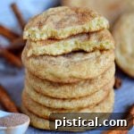 Stacked snickerdoodles on a blue board with the top cookie broken in half.
