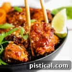 Crispy teriyaki chicken being picked up from a bowl with chopsticks.